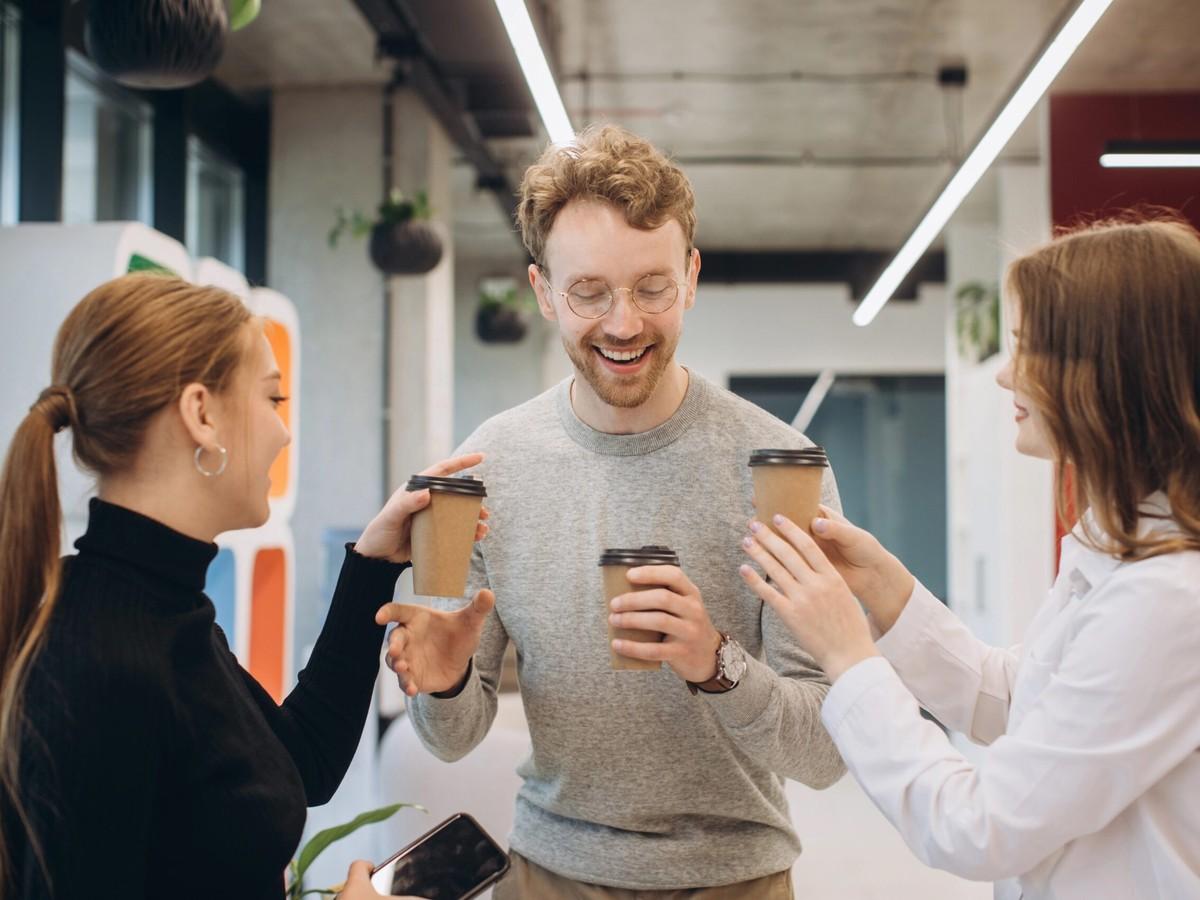 Zufriedene Kunden mit Kaffee aus dem Automaten im Büro