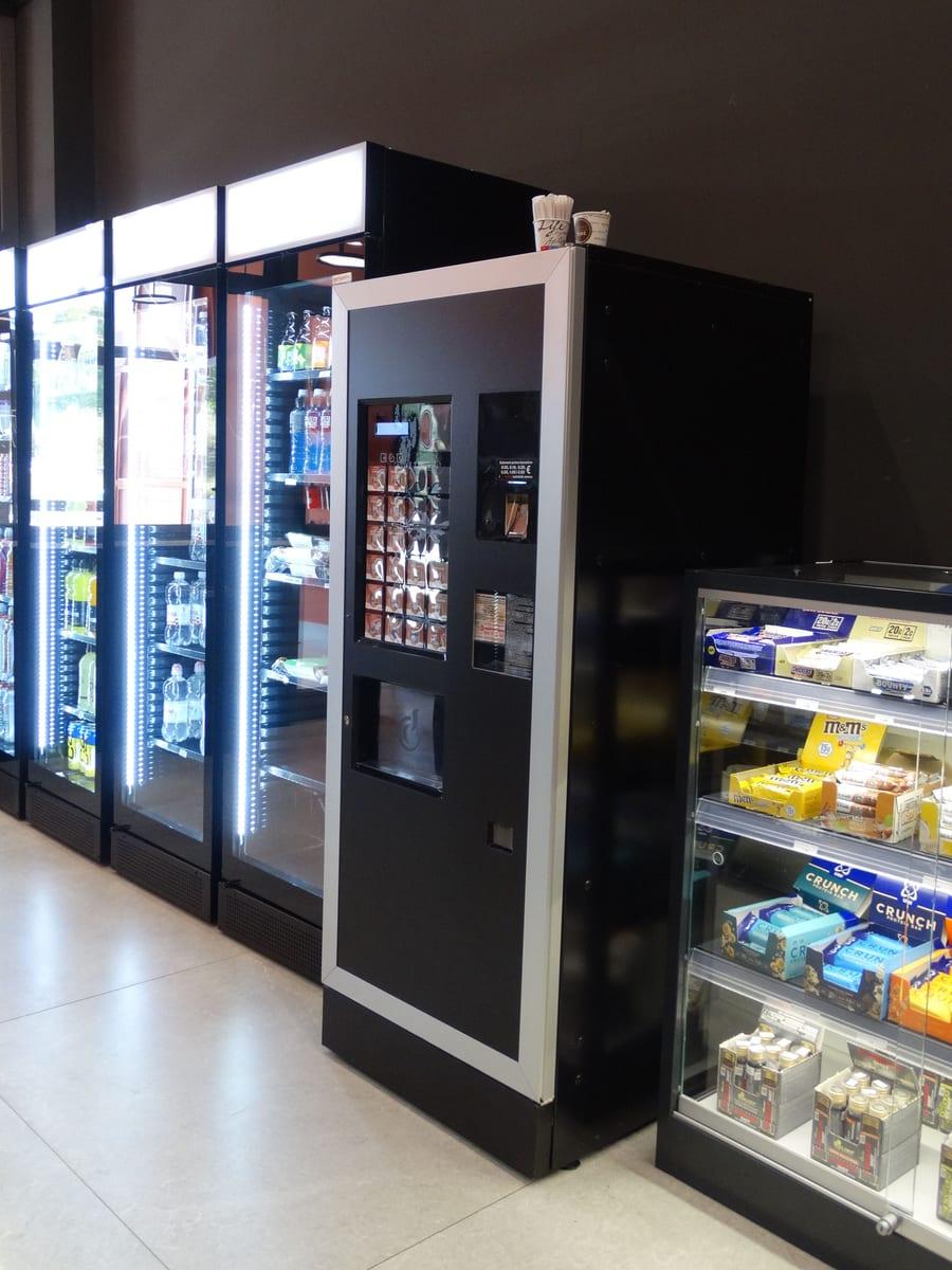 Kaffeeautomat neben Getränkekühlschränken in einem Geschäft